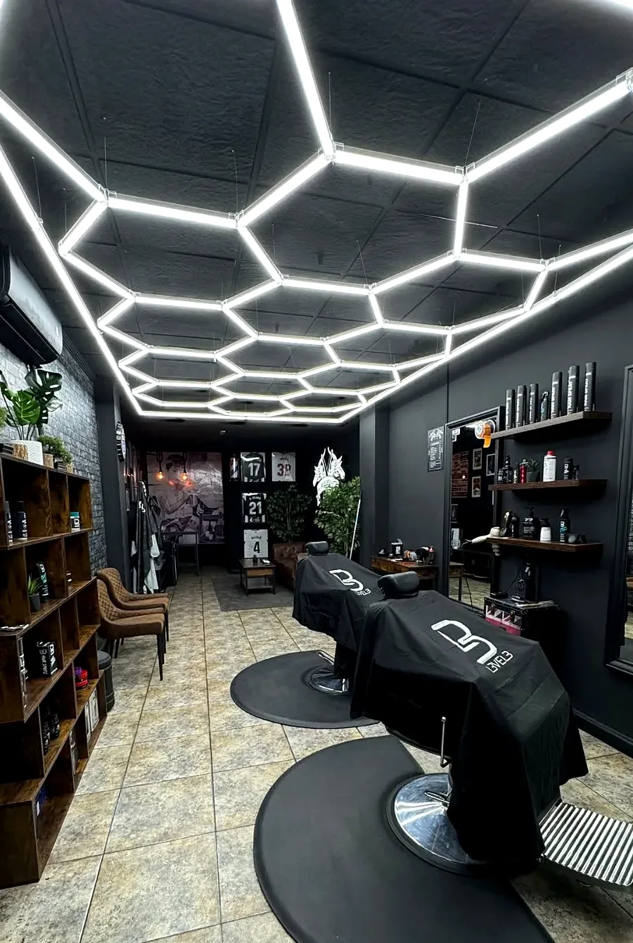 Interior de MK BarberShop con el techo de luces hexagonales y los sillones